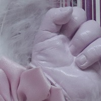 Babyhändchen und Füßchen in Rosa gehalten, Objektrahmen, Streifendesign und Schmetterlinge, mit Federn und Satinblume.